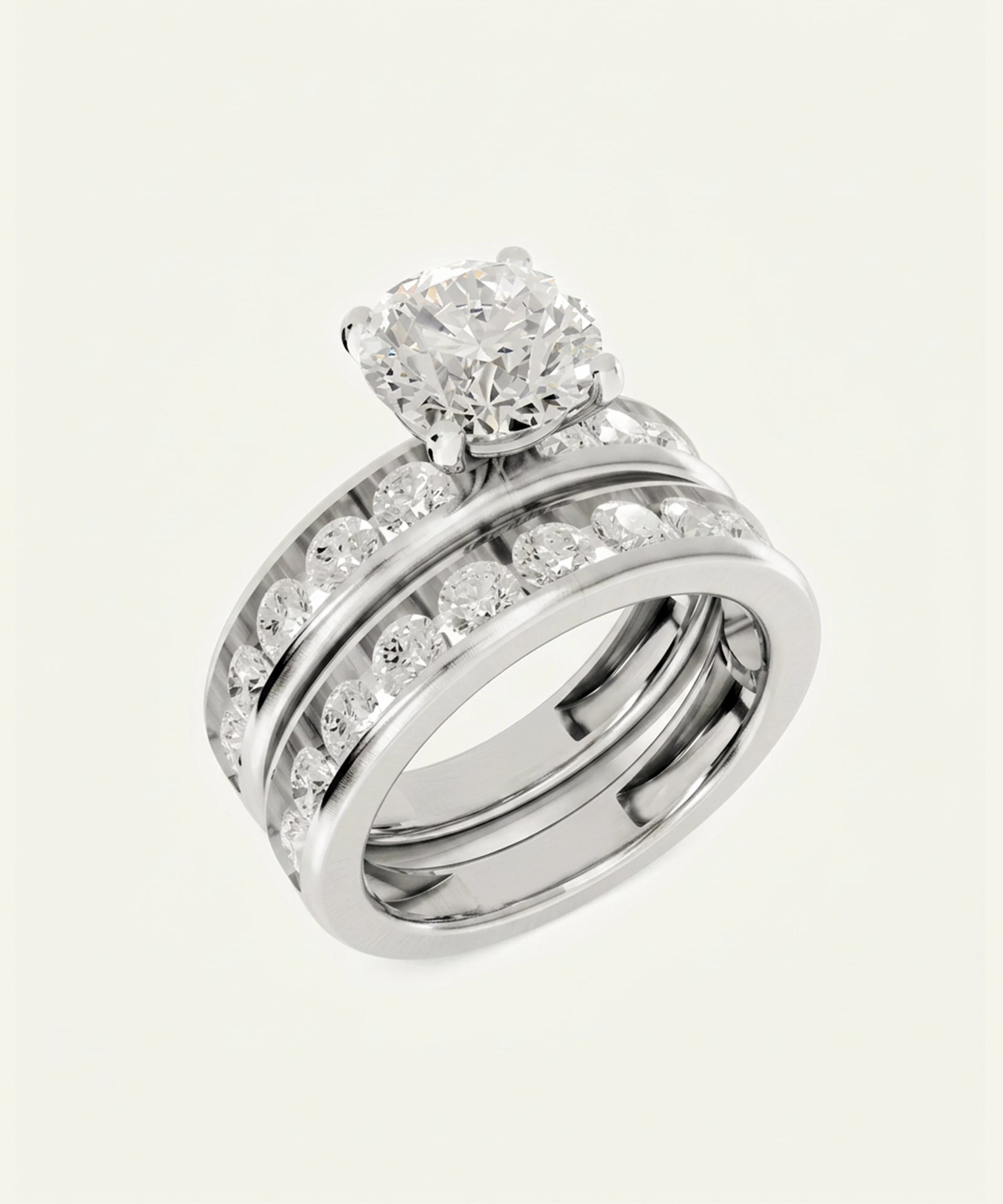 A silver-toned triple-band ring set featuring a round-cut diamond solitaire engagement ring and two matching band rings with pavé-set round diamonds, shown on a light cream background.