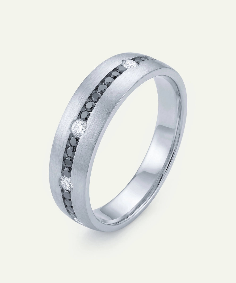 Silver ring with black and white gemstones on a light gray background