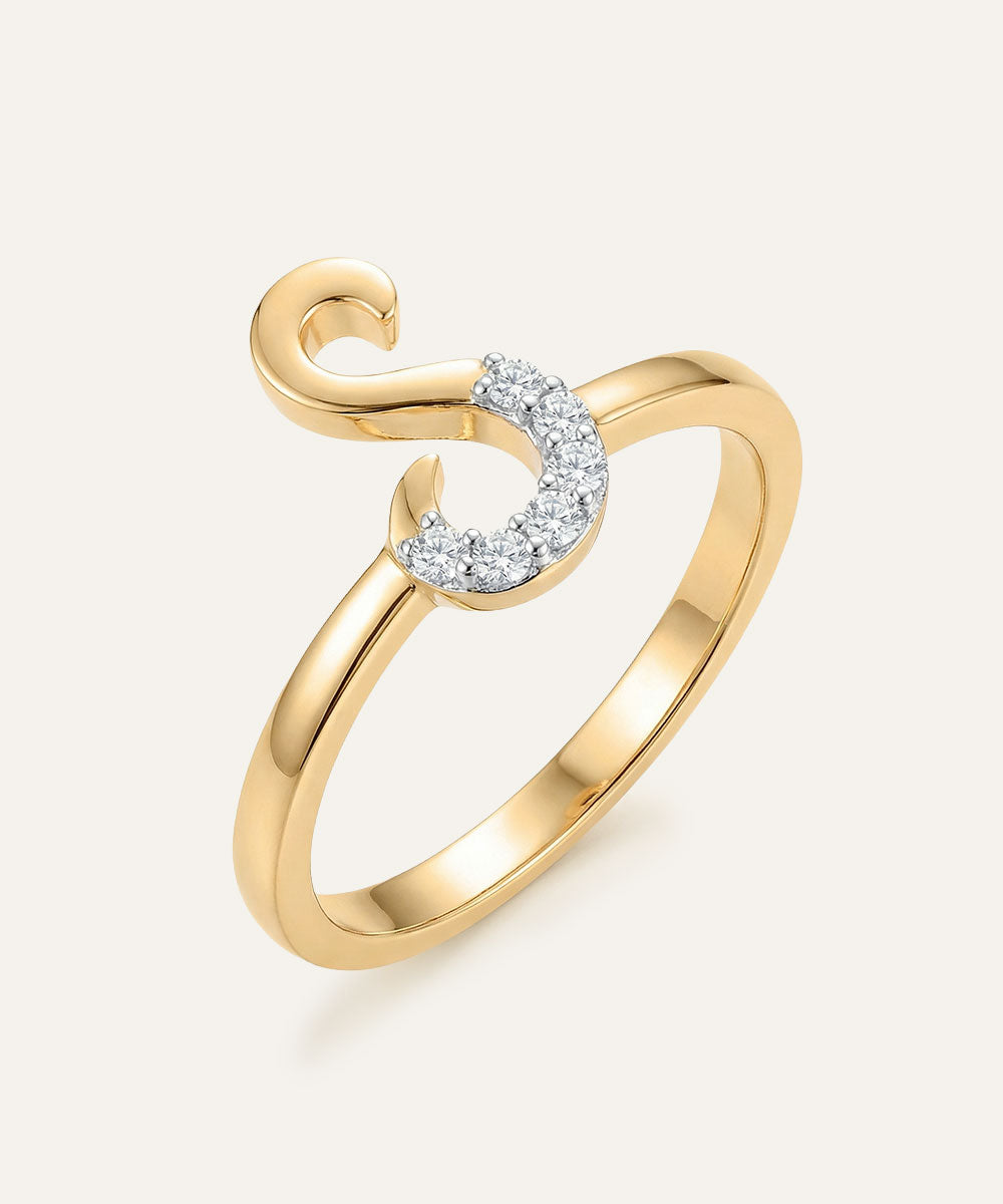 Gold ring with a heart-shaped diamond design on a light beige background