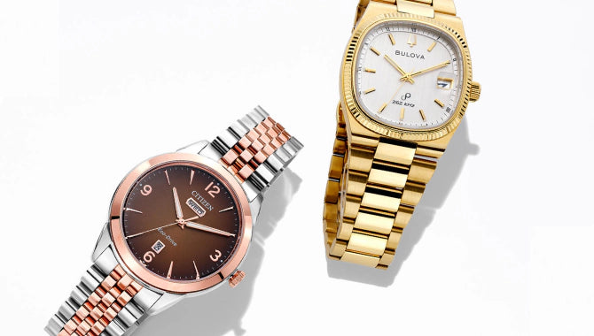 Two watches, one gold and one silver, on a white background